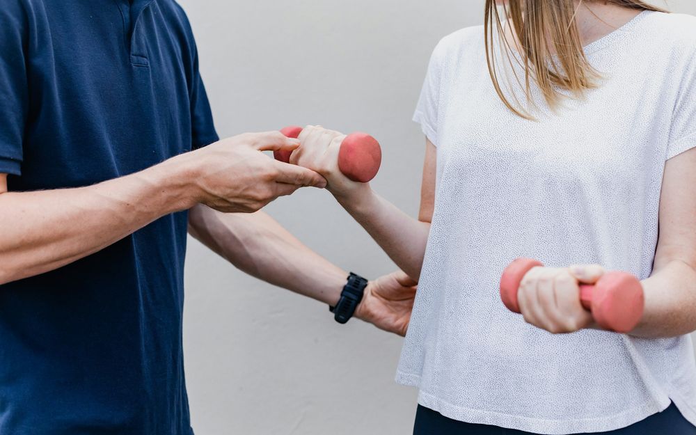 A therapist guiding a client through an arm exercise with light hand weights