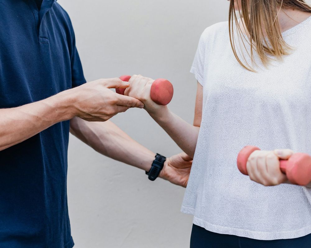 A therapist guiding a client through an arm exercise with light hand weights