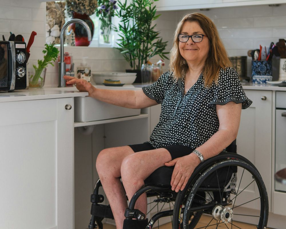 A woman in a wheelchair at an accessible kitchen sink at home